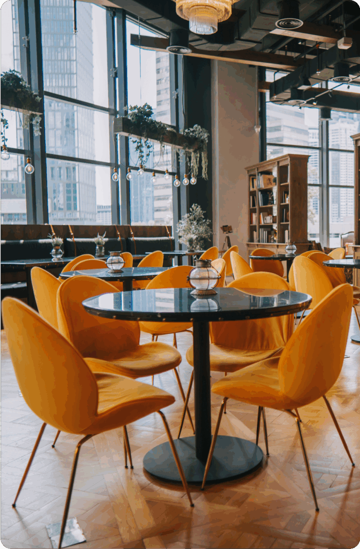 Modern cafe with orange chairs, large windows.