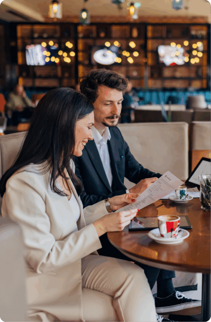 Two people reviewing documents in café.