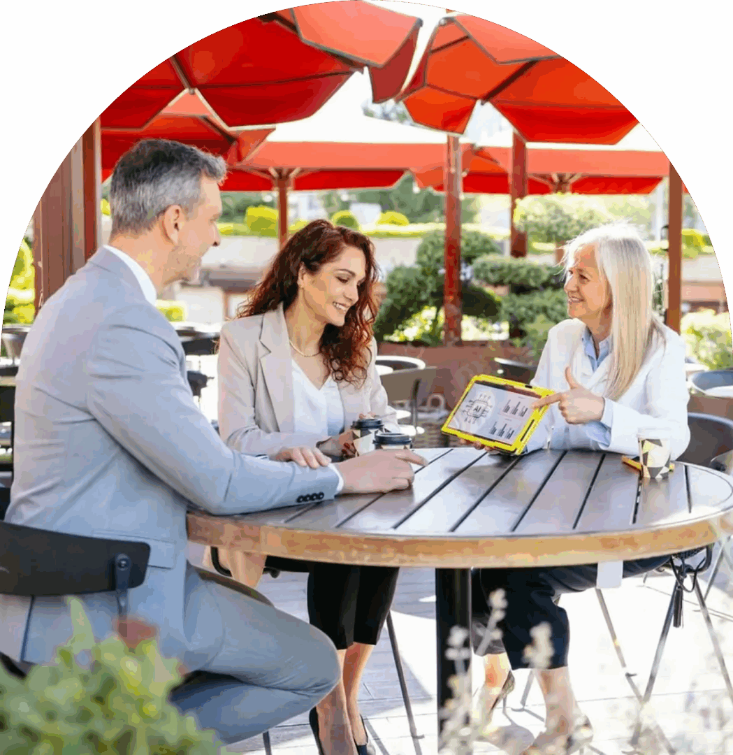 Three people discussing at an outdoor table.